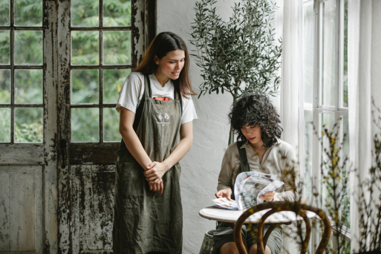 Woman helping another woman at the table with order.